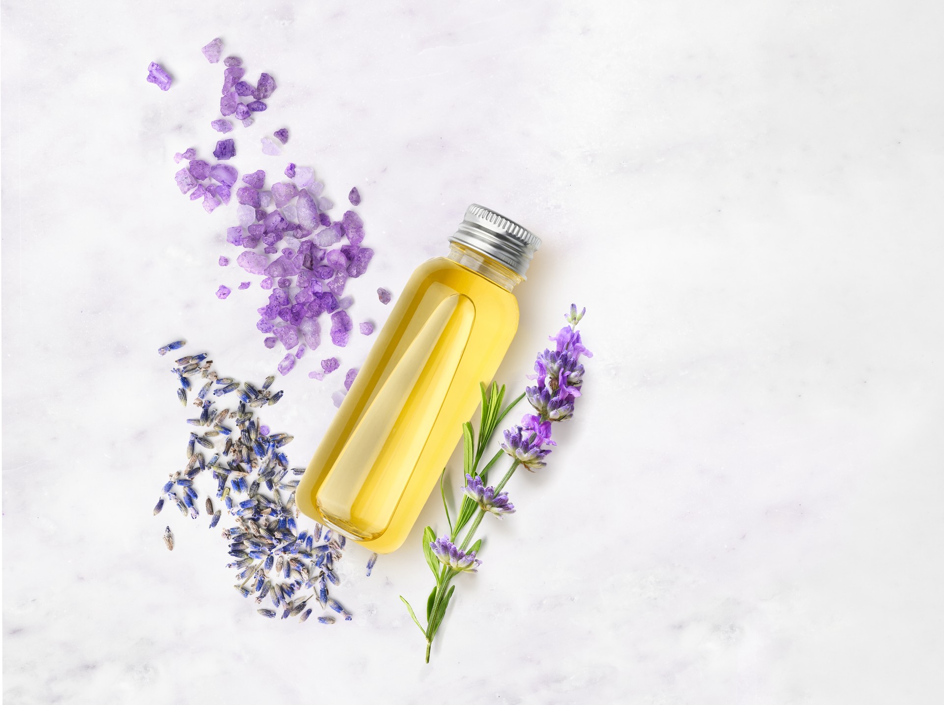 Essential oil and lavender salt with flowers on a marble table